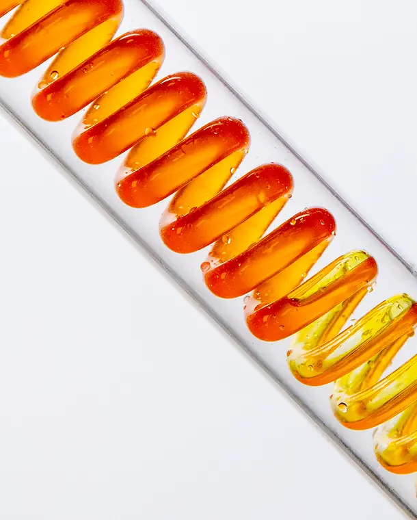 Row of orange-yellow gel capsules in glass.
