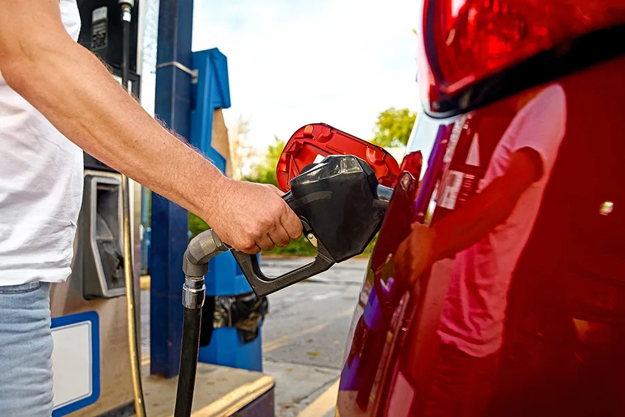 Person pumps gas into a red car