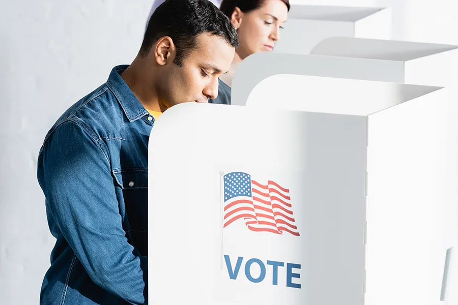 Man votes at white booth with US flag