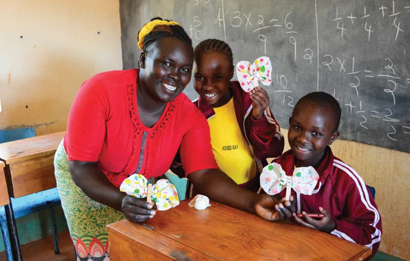 A teacher and students showing their hand crafts