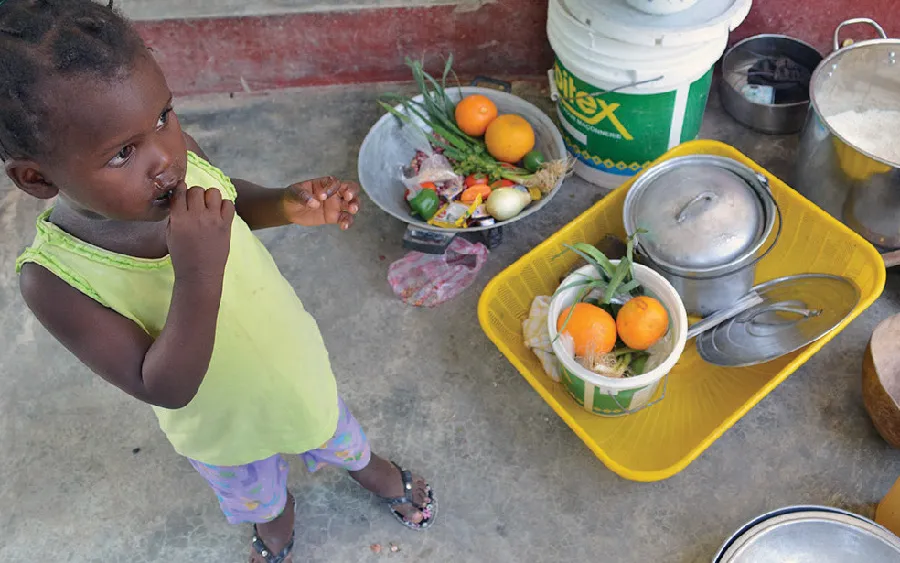 Girl eating near fruit and pots
