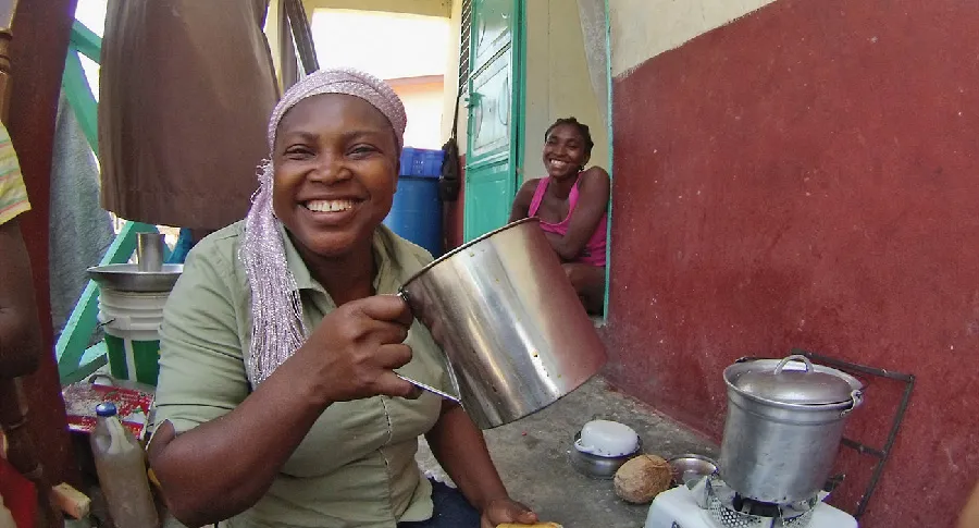 Smiling woman holding a metal pot outdoors