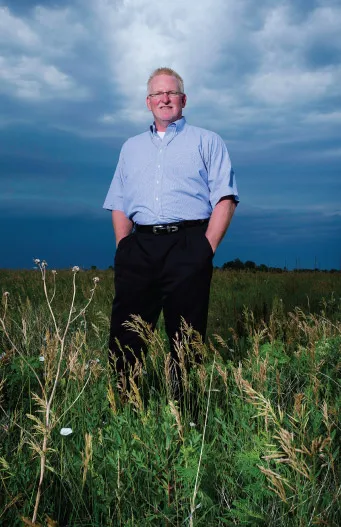Dean in blue shirt standing in field.