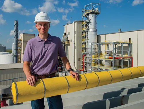 Worker in hard hat beside yellow pipe.