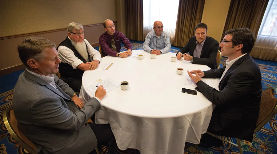 Six men in a business meeting around a round table.