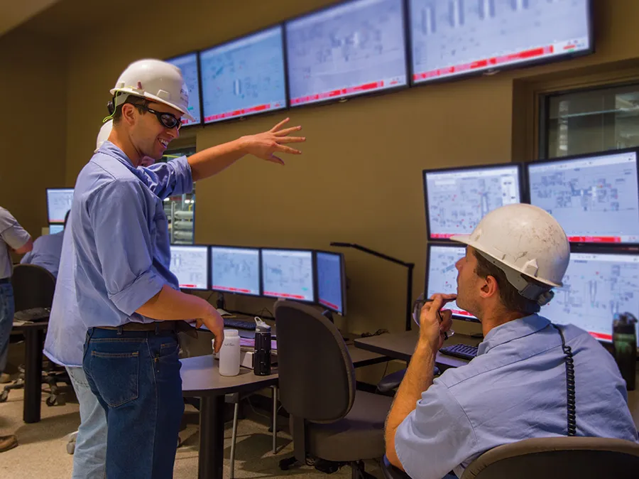 Two engineers in hard hats in a control room