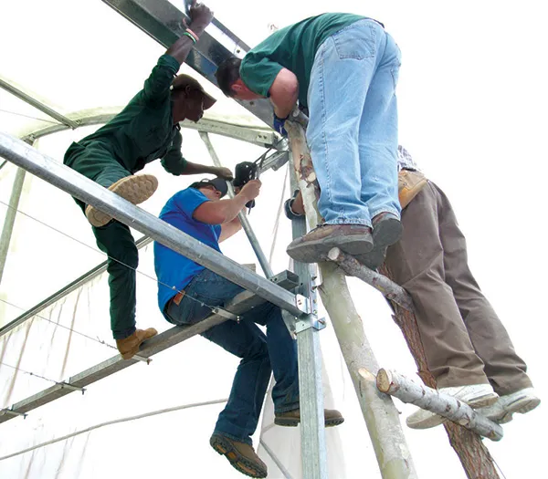 Neil Anderson, Ron Patton and Beau Schmaltz, POET team members, work with Johnston, Kenyan contractor, on a greenhouse bracket.