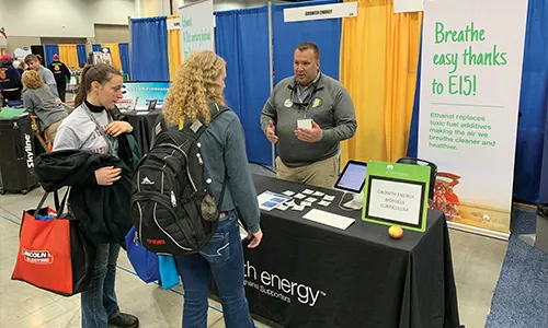 Man at energy booth explains product to visitors