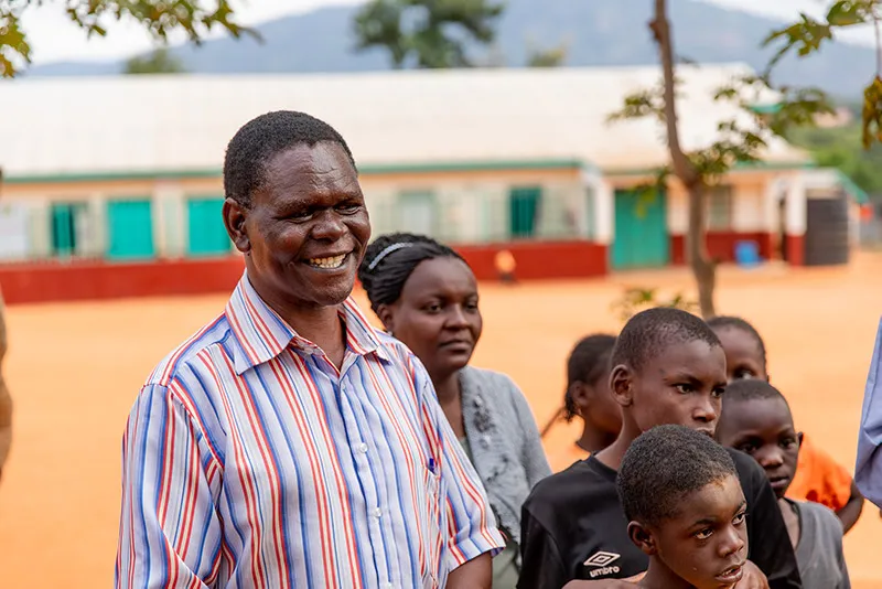 Smiling man in striped shirt with kids.