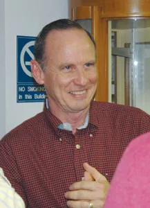 Roe wears a red checkered shirt talking to a person