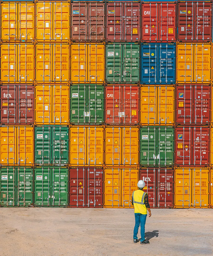 Worker in safety vest surveys stacked containers