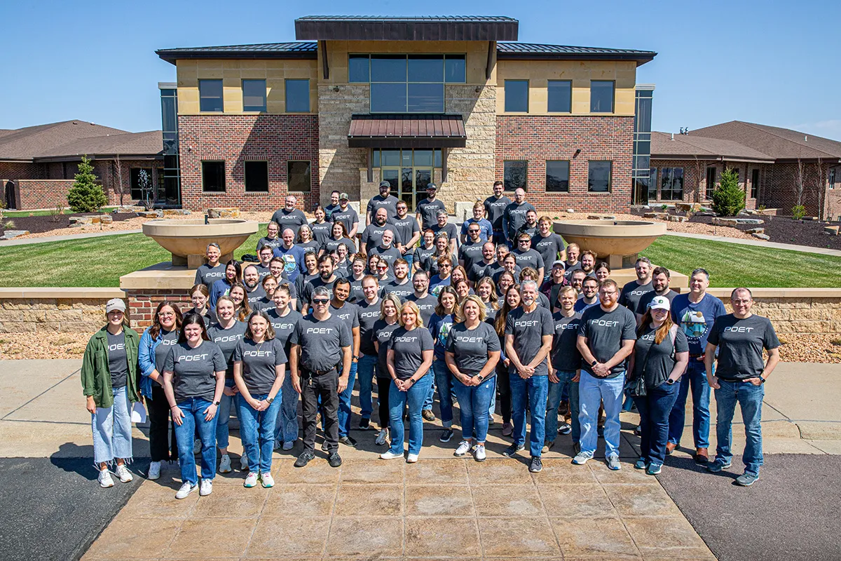 Group of people in gray POET shirts pose for a team photo