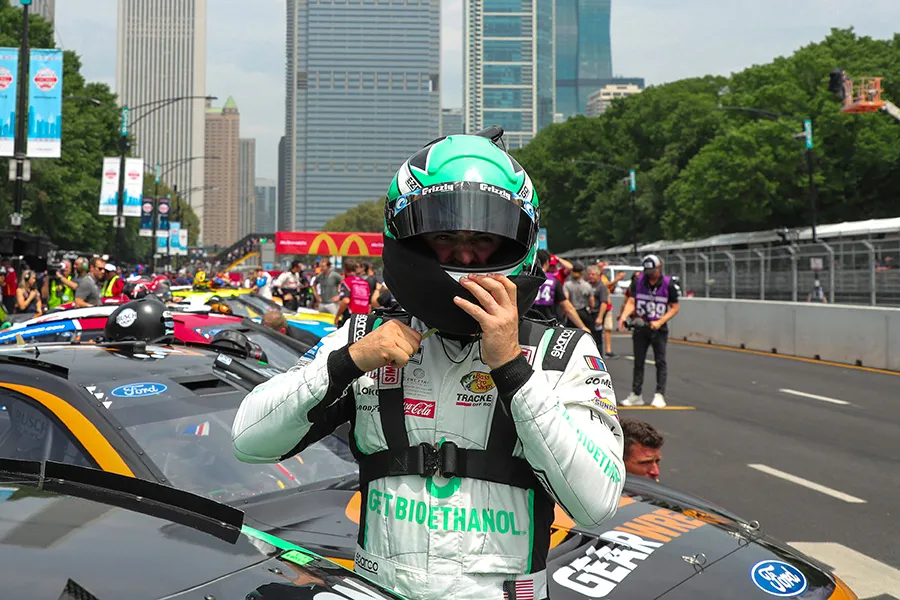 Racing driver in suit adjusting helmet.