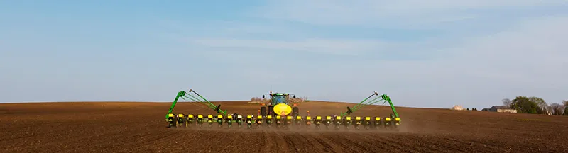 Tractor pulling large green sprayer across field