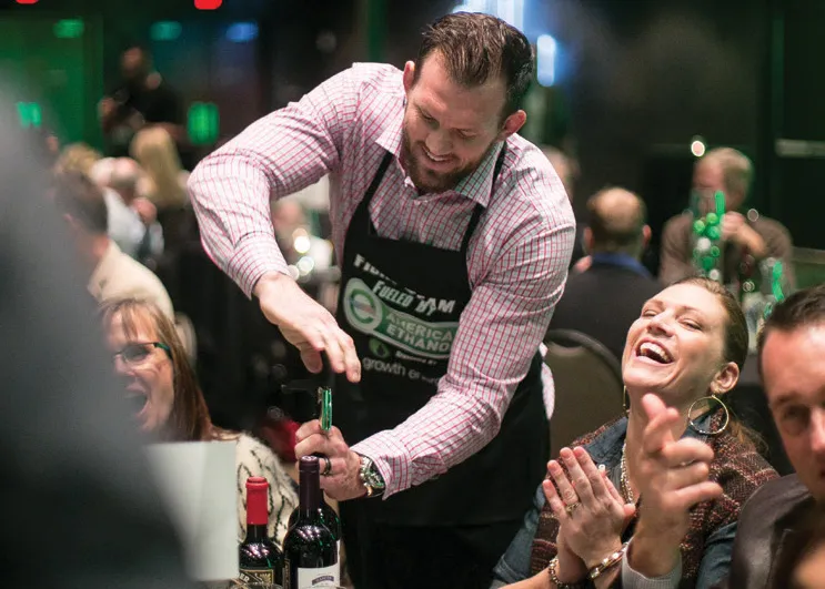 Ryan Bader opens a bottle of wine for Dine with a Fighter attendees.
