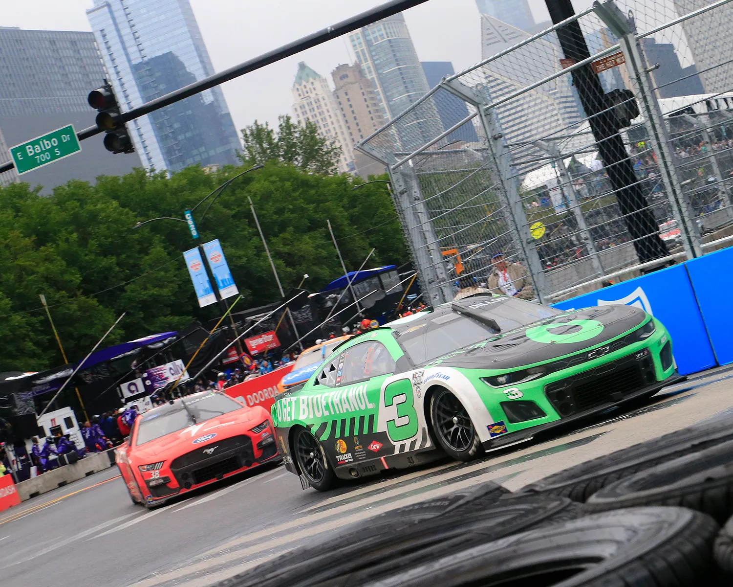 Green No. 3 race car drives on city street track.