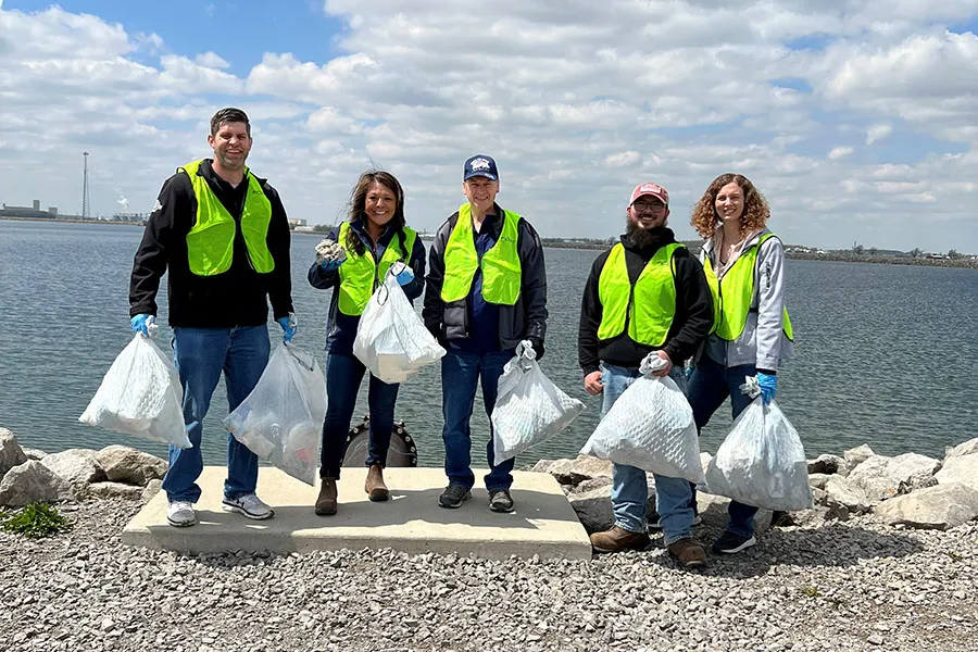Team in neon vests with trash bags by lake