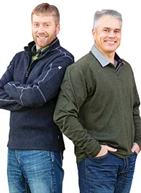 Two men standing back-to-back in casual sweaters.