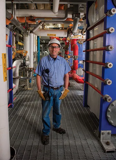 Schauer in hard hat amid pipes.