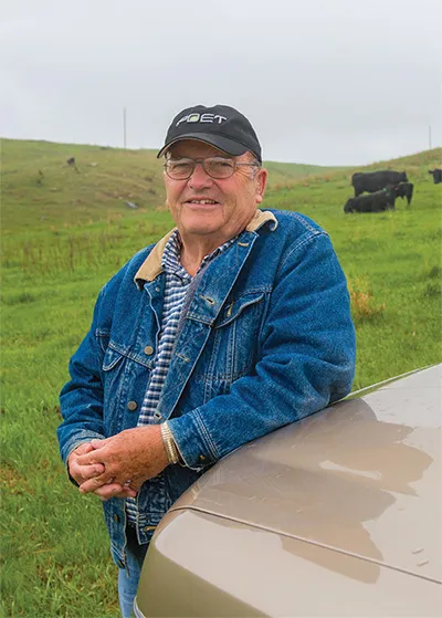 Jerry leaning on beige car in a field