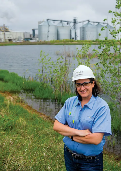 Pitz in blue shirt wearing hard hat near water.