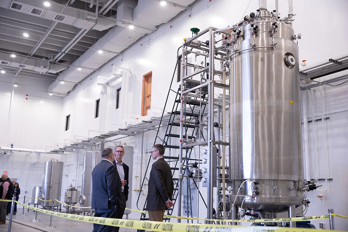 Experts discuss near a stainless steel reactor.