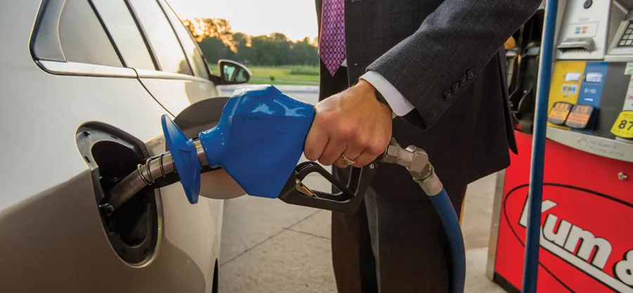 Businessman fueling car at gas pump.