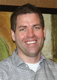 A man headshot smiling at the camera