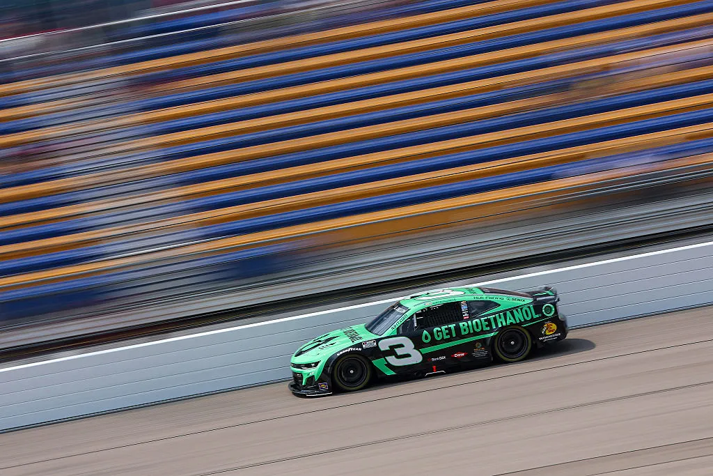 Green stock car racing on track.