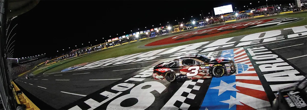 NASCAR car #3 crosses finish line at night.