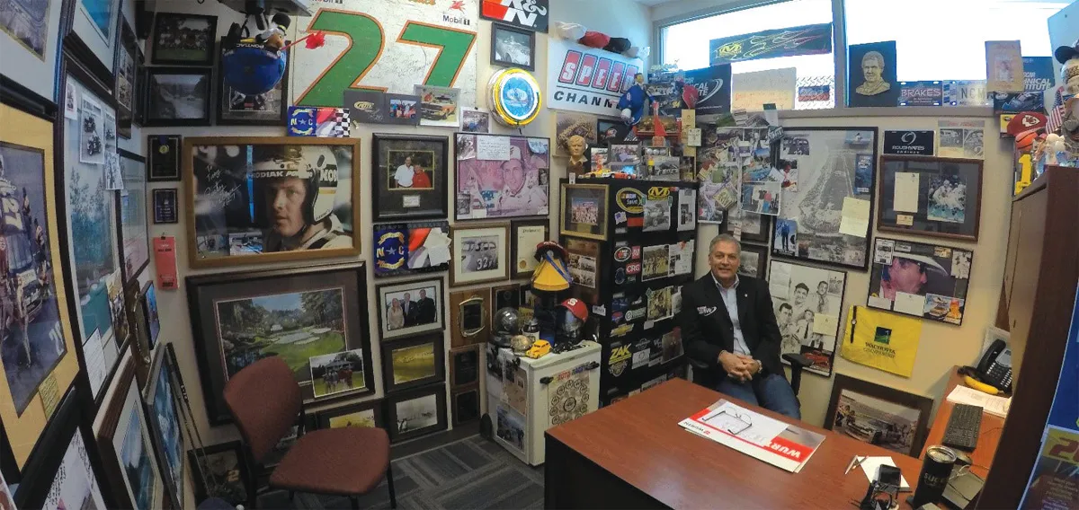Man sits in cluttered memorabilia-filled office.