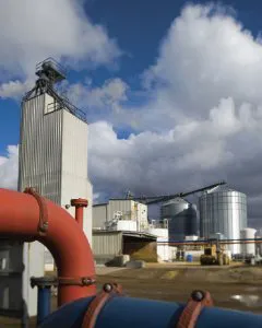 Grain storage facility with tall silo and pipes