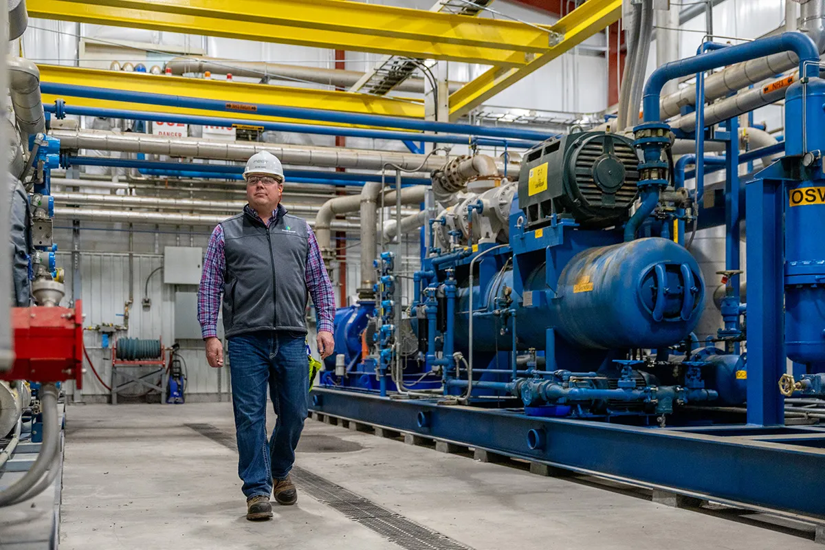Adam Wirt in hard hat walks through industrial plant