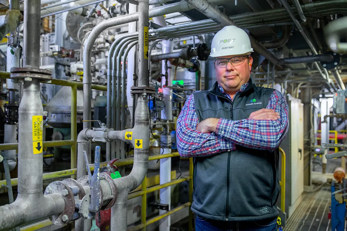 Adam Wirt in hard hat beside industrial piping