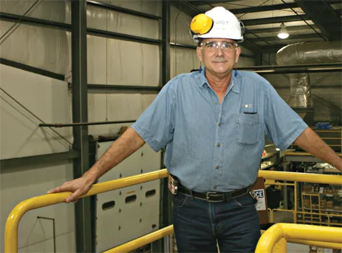 Steve standing inside the factory wearing headphone and white hat