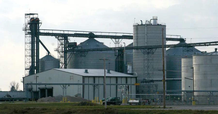 Grain silo and conveyor system at industrial site.