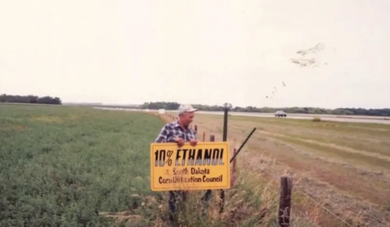 Man holds 10% Ethanol sign by field.