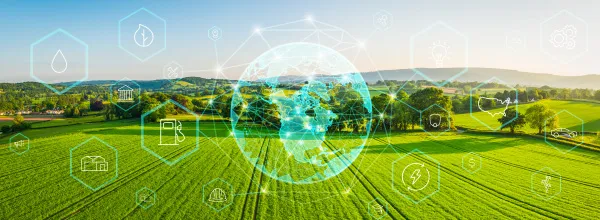 Globe with holographic icons over a green farm.