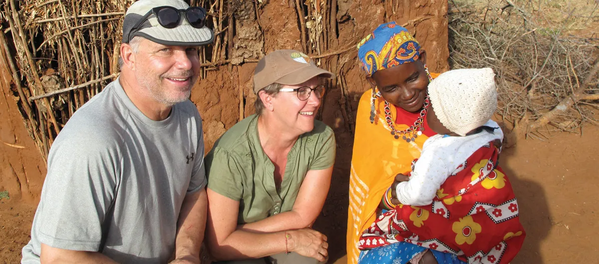 Three adults converse with a child outdoors