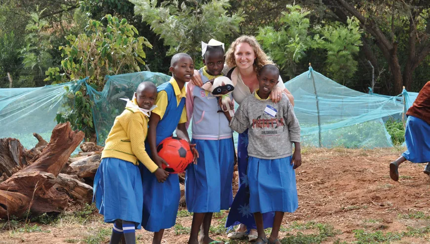 Students and a woman smiling at the camera