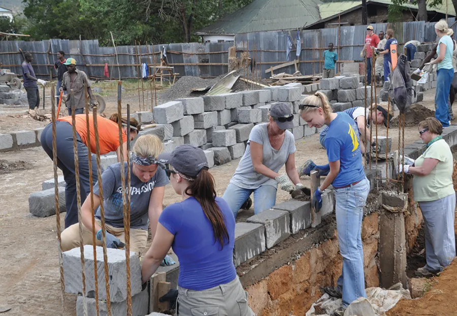 Miranda and Alyssa Broin, Debbie Anderson and Kayla Schlechter apply mortar and lay brick to form the dormitory walls.