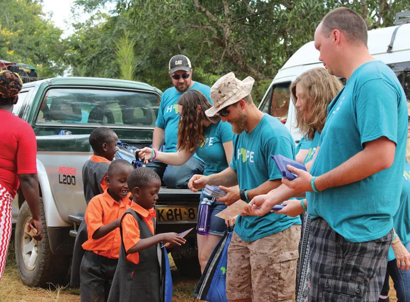 POET team members hand out gifts to students.