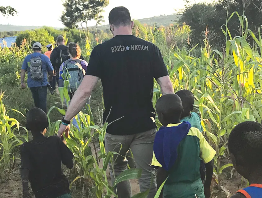 Kids and adults walking together through a cornfield on a farm