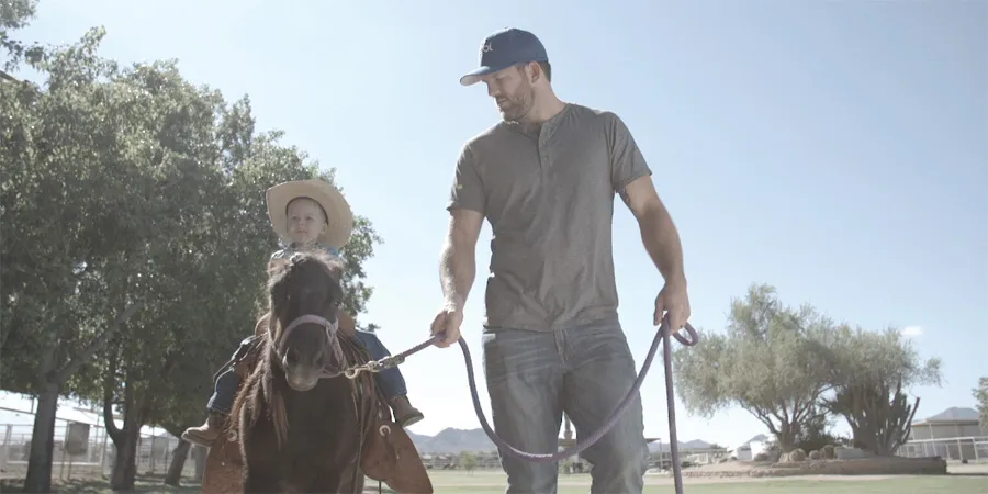 Bader holding a pony’s lead rope while a child rides the horse.