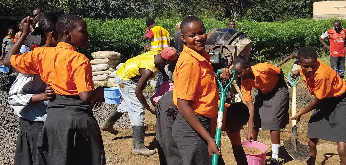 Students in orange uniforms dig with shovels.