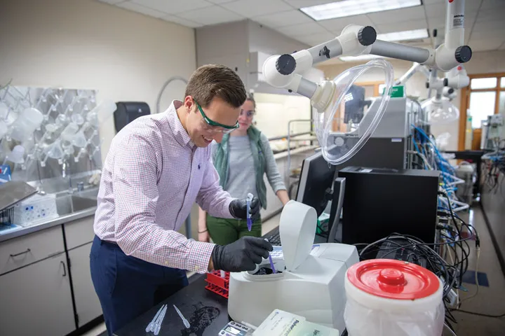 A man working in a lab while a woman observes him