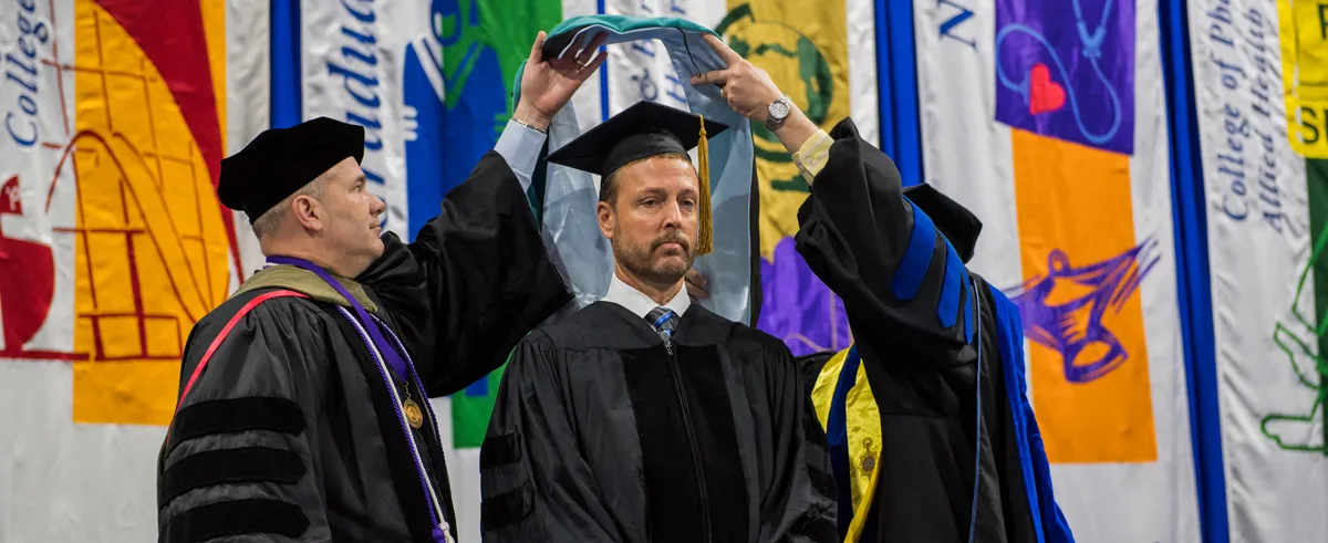 Two people holding a book above a Jeff's head
