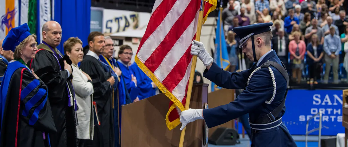 A man installing a U.S. flag at graduation