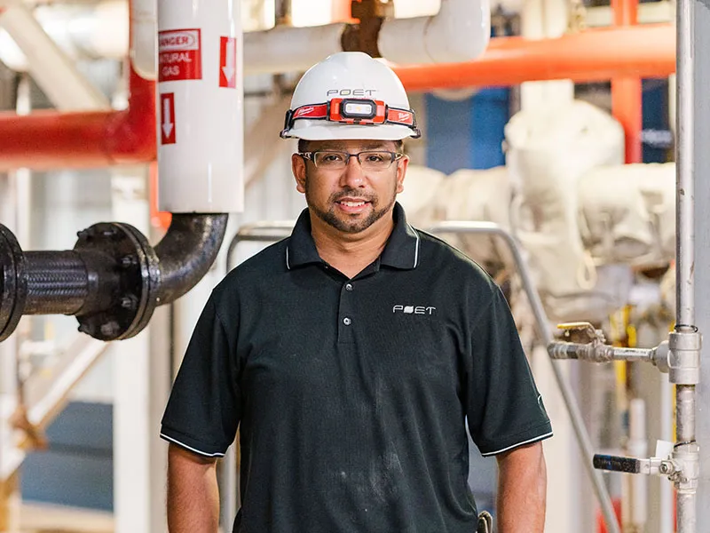 Factory worker in hard hat stands in plant