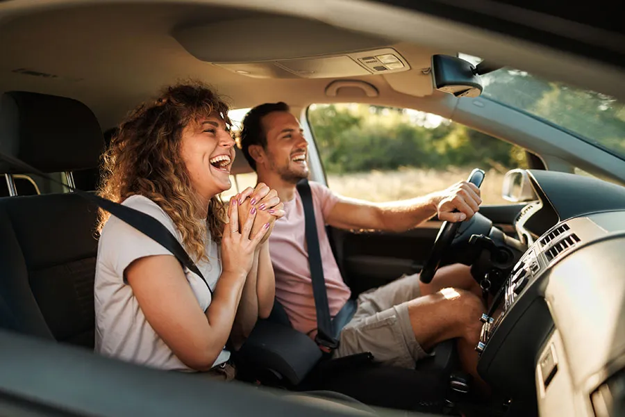 A man and a woman laughing inside the car